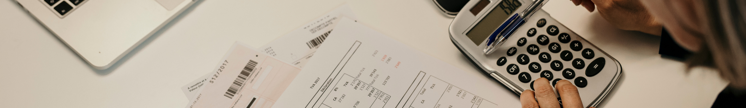 Gestion d'entreprise et d'organisation avec EnfinFidu Ordinateur avec calculatrice, documents fiscaux et bilan, illustrant l'accompagnement personnalisé des PME suisses romandes par EnfinFidu