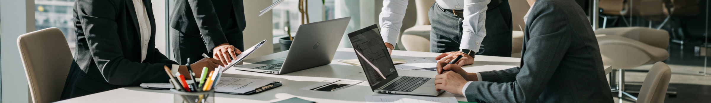 Quatre entrepreneurs, deux hommes et deux femmes, travaillent autour d’une table avec ordinateurs pour élaborer ensemble le business model canvas de leur entreprise