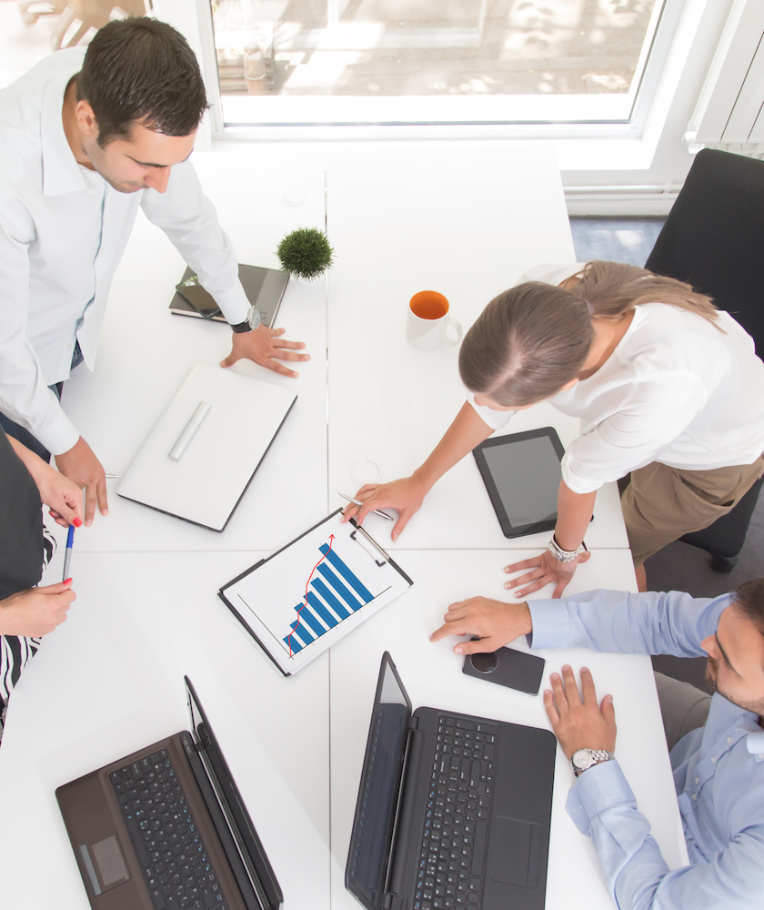 Entrepreneurs échangeant autour des priorités stratégiques de leur projet Entrepreneurs réunis autour d’une table analysant des graphiques pour structurer la stratégie d’une start-up en Suisse romande